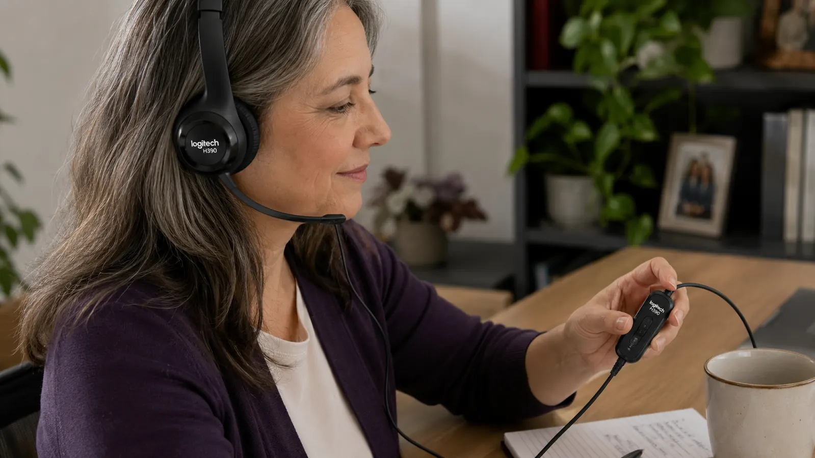 Hand adjusting the in-line volume and mute control on the Logitech H390 headset cable