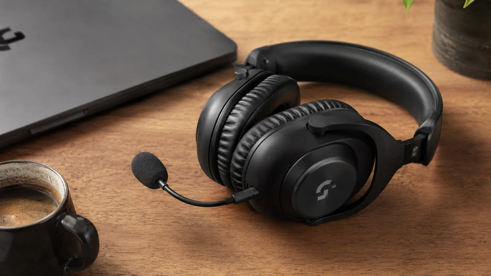 Close-up of the Logitech H390 headset resting on a desk next to a laptop, boom microphone visible