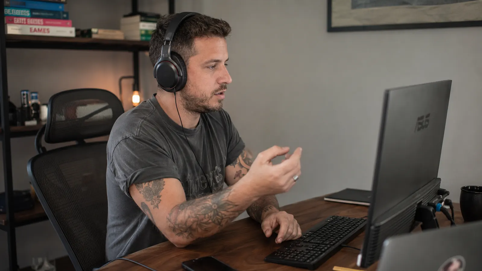 Person on a video call wearing a wired headset at a home office desk with a UPS and cable tray visible
